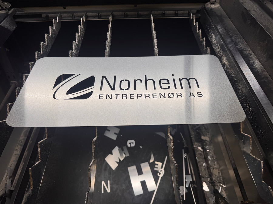 Metallsjablong med logoen til Norheim Entreprenør klar for laserskjæring