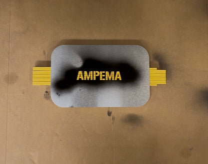 Metallsjablong festet med tape over gul AMPEMA-merking